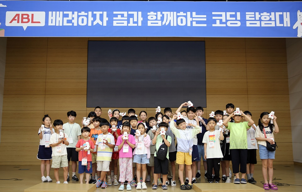 ABL 배려하자 곰과 함께하는 코딩 탐험대 행사에 초청된 임직원 자녀 30명이 배려곰 인형을 손에 쥐고 단체사진을 찍고있는 모습
