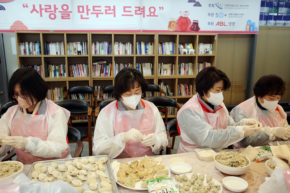 사람들이 테이블 앞에 앉아서 만두를 빚고있는 모습의 사진