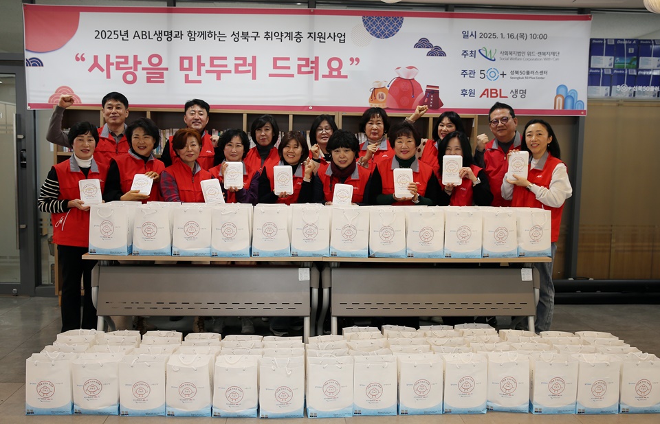 2025년 ABL생명과 함께하는 성북구 취약계층 지원사업, 사랑을 만두러 드려요, 일시 : 2025.1.16(목) 10:00, 주최 : 서울복지법인 위드-캔복지재단, 주관 : 50+ 성북 50플러스 센터, 후원 : ABL생명, 문구가 쓰여진 현수막 앞에 ABL생명 빨간색 조끼를 입은 봉사단 사람들이 직접 만든 만두를 손에들고, 앞에는 만두가 든 쇼핑백을 가득 나열해서 단체사진을 찍고있는 모습의 사진